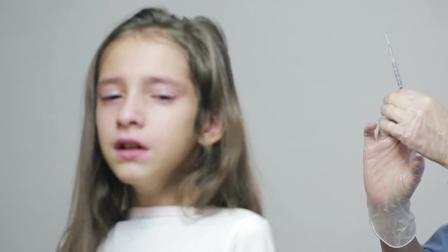 little girl is afraid of the doctor with a syringe. baby cries afraid injection