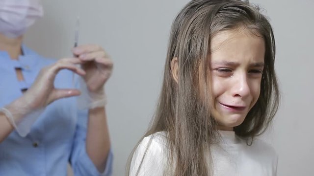 little girl is afraid of the doctor with a syringe. baby cries afraid injection