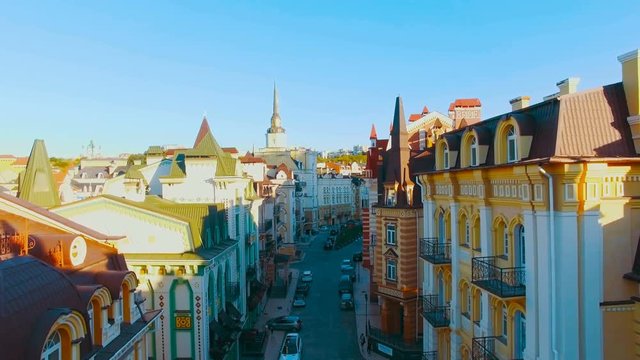 Drone Camera Moves at the Level of the Roofs of Buildings on the Old Narrow European Streets with Colorful Houses and Pedestrians at Sunset, Shot in 4K UHD