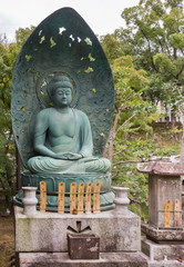 Kyoto, Japan - September 15, 2016: Green statue of Amitabha Buddha, meditating while sitting on lotus. Large shell as background and set in the garden.