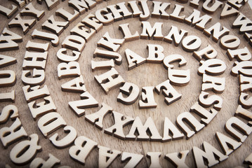 Wooden alphabet twisted like a spiral on a wooden background