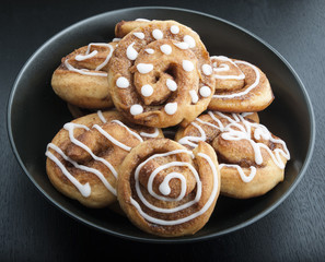 Twisted buns with cinnamon and icing sugar on a black background
