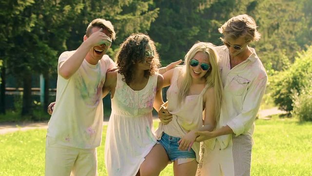 Two couples enjoying holidays and smudging colorful powder at Holi festival