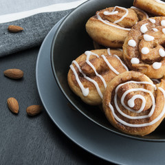 Buns with cinnamon and icing sugar. Black table setting