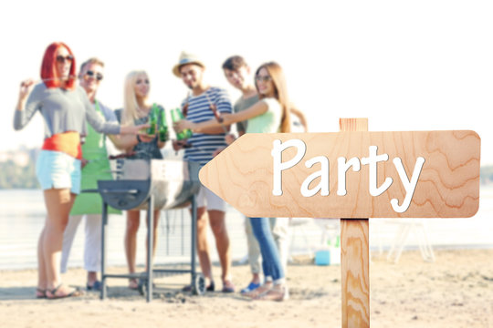 Wooden sign arrow with text PARTY on blurred people background
