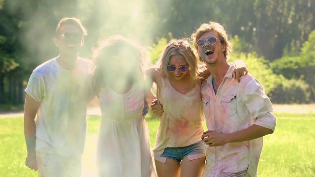 Happy young people dancing at Holi festival, throwing colorful powder in air