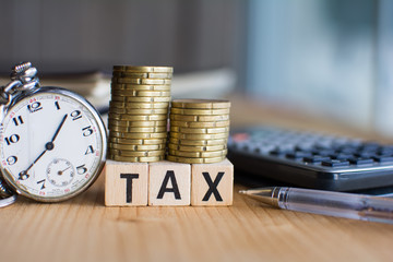 Close-up Of  the word Tax  On Wooden Blocks and a pocket watch and a calculator  on the background