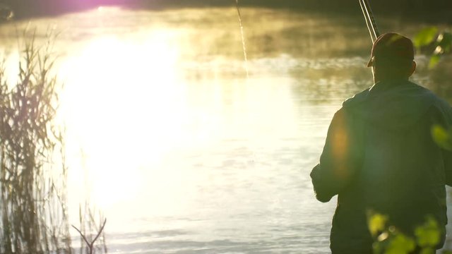 fisherman throws a fishing tackle in the river at dawn