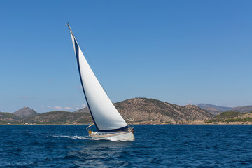 Obraz na płótnie Canvas Luxury yacht with white sails in the Aegean sea near the coast of the Greek Islands.