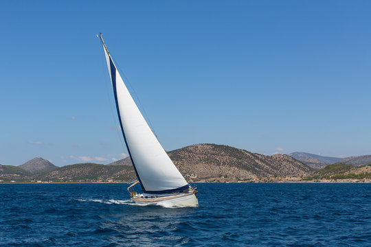 Luxury yacht with white sails in the Aegean sea near the coast of the Greek Islands.