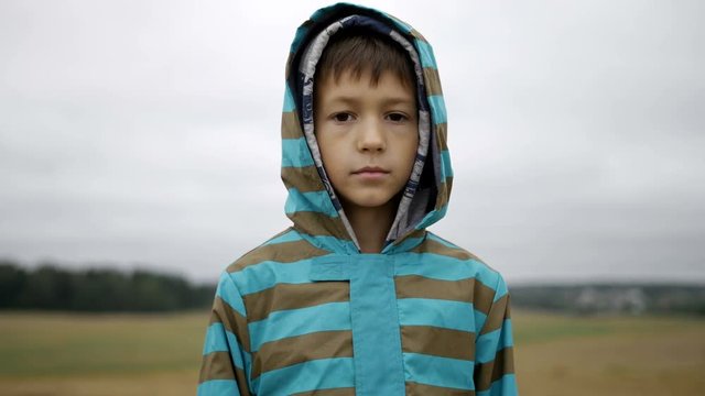 Portrait of a boy in the hood standing and looking at the camera in the evening
