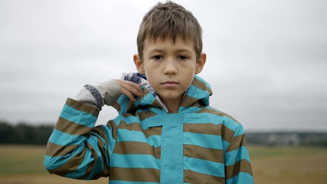 Portrait of a boy takes off the hood and looking at the camera