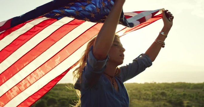 Beautiful young woman at with American flag at sunset, fashion lifestyle