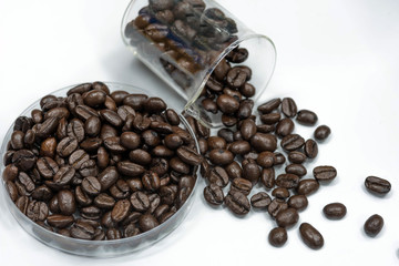 Fresh roasted coffee beans in plate and beaker.