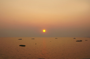 A boat in the distance on the sea at sunset