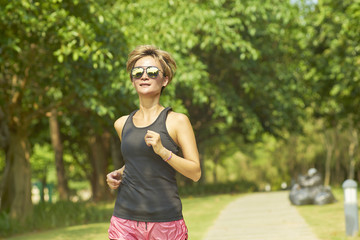 young woman jogging in green park in morning