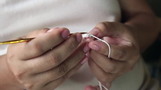 Close up of young woman's hands crocheting slow motion