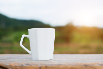 White cup of hot coffee on mountain natural green background.