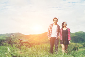 Young hipster couple holding hands walking on the meadow relaxin
