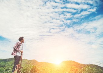 Young hipster man holding a guitar with a walking in nature, Rel