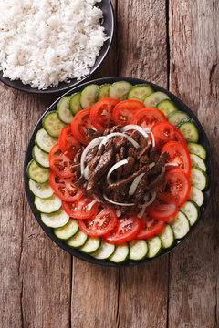 Cambodian beef Lok Lak with fresh vegetables and a side dish of rice. Vertical top view