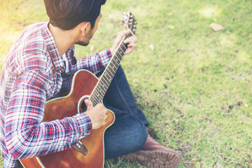 Young hipster man practiced guitar in the park,happy and enjoy p