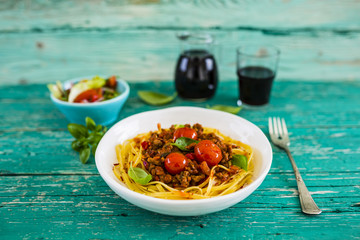Delicious bavette pasta with bolognese sauce and fresh herbs on wooden table. Italian food. 
