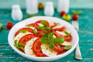 Delicious caprese salad with ripe tomatoes and mozzarella cheese with fresh basil leaves. Italian food. 