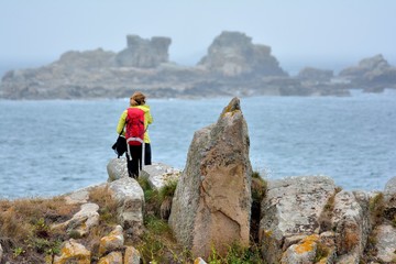 Obraz premium Une jeune randonneuse prend des photos de la côte et la mer à Plougrescant en Bretagne