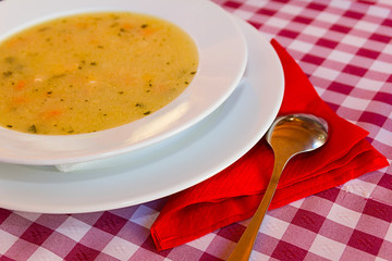 Chicken soup in a white bowl with spoon.