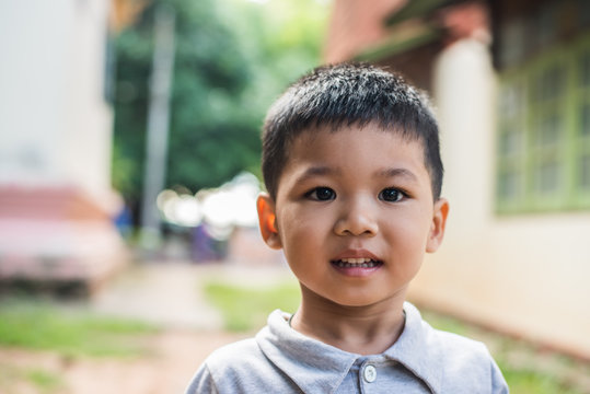 Close Up Portrait Of Asian Boy Smiling In The Park.