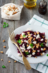 Salad of beetroot, feta and walnuts with leaves of parsley on the old wooden background. Selective focus.