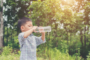 Little cute asian boy drink water on the roadside.