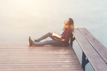 young beautiful hipster woman relaxing sitting on pier reading b