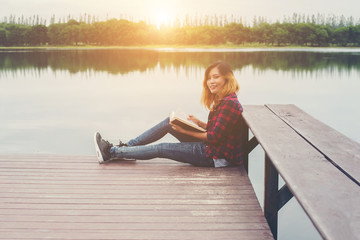 Fototapeta na wymiar young beautiful hipster woman relaxing sitting on pier reading b