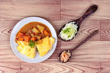 Omelet rice topped Japanese yellow curry  with sliced cabbage and pickled ginger are popular food for health. 
