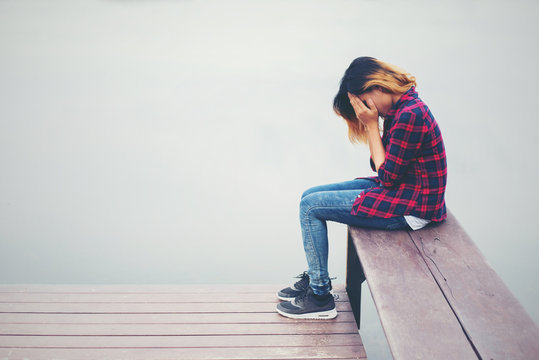 Sad hipster woman sitting on the pier with sadness.