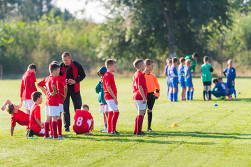 Boys playing football soccer game on sports field