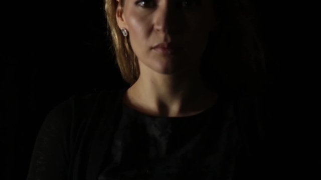 young woman appearing from darkness in camera