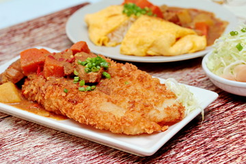 Close up deep fried dolly fish in Japanese style topped yellow curry with sliced cabbage and pickled ginger. Selective focus.