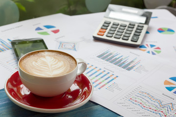 concept image of served Latte art coffee during checked summary graph in paper and mobile phone