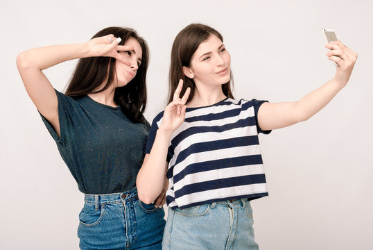 Positive friends portrait of two girls making selfie, funny face
