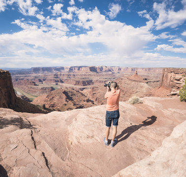 USA, Utah, Young man standing on Dead Horse Point photographing Colorado River