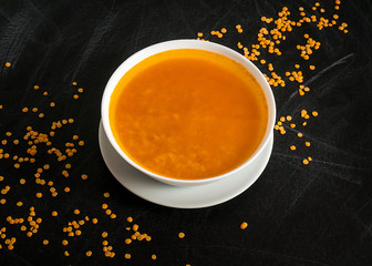 Delicious cream soup on dark background, red lentil. Top view