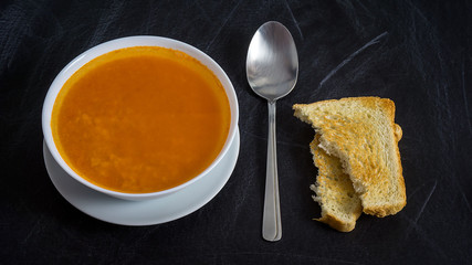 pumpkin soup with toast on dark background, top view