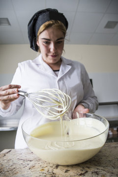 Woman thickening melted white chocolate with wire whisk