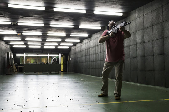 Man aiming with a tactical weapon in an indoor shooting range