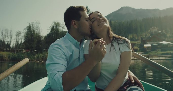 A beautiful  couple kissing in a boat at lake with a lovely smile