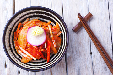 Top view of a bowl of traditional Korean Kimchi on a wooden table.