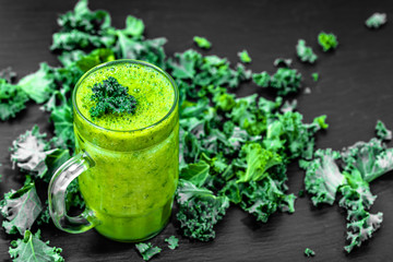 Healthy smoothie with green kale leaves in a glass on black background - obrazy, fototapety, plakaty